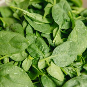 Close-up of fresh spinach leaves with water droplets, highlighting their vibrant green color and freshness.